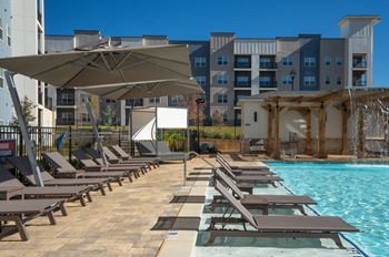 A pool area with sun loungers and a waterfall.